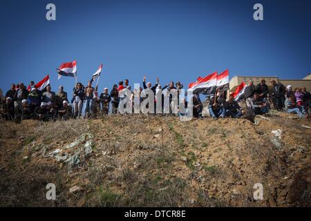 (140215) -- MAJDAL SHAMS, Feb 15, 2014 (Xinhua) -- i membri della comunità i drusi attesa bandiere siriano durante un rally in Majdal Shams, Drusi un villaggio con una popolazione di 11.000 adiacente ad interim recinzione di confine nel nord del Golan e situata nel cuore di un conflitto tra Israele e la Siria, su 14 Febbraio, 2014. Centinaia di membri della comunità i drusi hanno preso parte al rally qui il venerdì, protestando contro Israele l'annessione delle alture del Golan in 1981. Israele catturato le alture del Golan in una guerra 1967 e poi annesso il territorio strategico che si affaccia norther Foto Stock