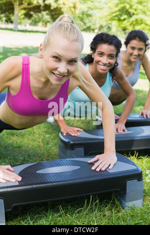 Donna sorridente facendo step aerobics Foto Stock