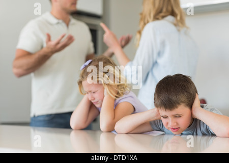 I bambini che copre le orecchie mentre i genitori sostenendo Foto Stock