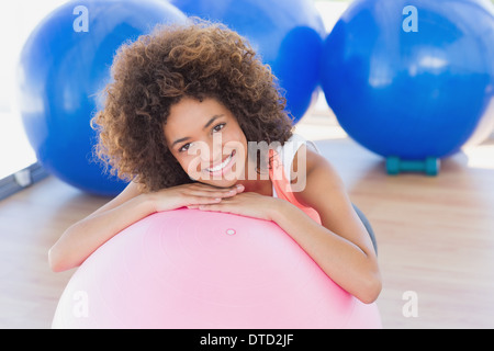 Sorridente giovane donna con sfera di fitness in palestra Foto Stock