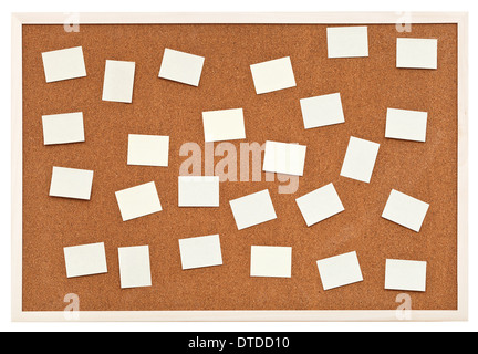 Molti piccoli fogli di carta sul bollettino bacheca di sughero isolati su sfondo bianco Foto Stock