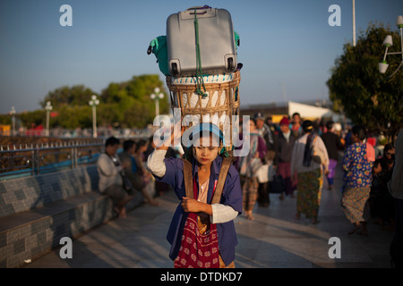 Una donna che portano i turisti il bagaglio dall'hotel alla stazione dei bus Kyaiktiyo Pagoda 'Golden Rock' a Kyaiktiyo, Myanmar su Sat Foto Stock