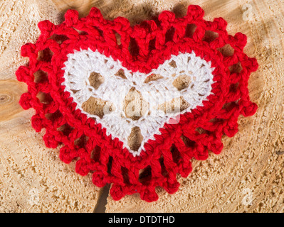 Forma di cuore realizzato in tessuto di colore rosso su base di legno Foto Stock