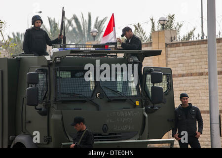 Il Cairo, Egitto. 16 feb 2014. Un poliziotto mette una bandiera nazionale su un furgone della polizia di fronte al Cairo Accademia di polizia del Cairo in Egitto, Feb 16, 2014. Un tribunale del Cairo, interrotta domenica la prova d'Egitto dell ex presidente Mohamed morsi su accusa di spionaggio a febbraio 23, agenzia ufficiale MENA segnalati. Credito: cui Xinyu/Xinhua/Alamy Live News Foto Stock