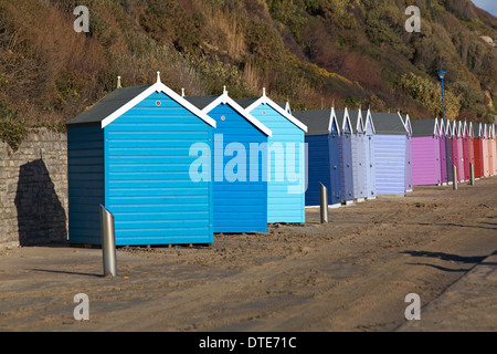 Capanne sulla spiaggia blu e viola dislocate che si trovano di fronte alla strada sbagliata e fuori linea dopo le recenti tempeste di vento cattivo tempo a Bournemouth, Dorset UK nel mese di febbraio Foto Stock