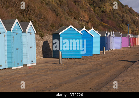 Capanne sulla spiaggia blu e viola dislocate che si trovano di fronte alla strada sbagliata e fuori linea dopo le recenti tempeste di vento cattivo tempo a Bournemouth, Dorset UK nel mese di febbraio Foto Stock