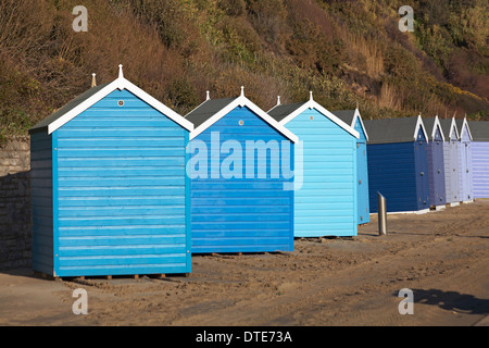 Capanne sulla spiaggia blu e viola dislocate che si trovano di fronte alla strada sbagliata e fuori linea dopo le recenti tempeste di vento cattivo tempo a Bournemouth, Dorset UK nel mese di febbraio Foto Stock