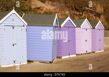 Capanne sulla spiaggia blu e viola dislocate che si trovano di fronte alla strada sbagliata e fuori linea dopo le recenti tempeste di vento cattivo tempo a Bournemouth, Dorset UK nel mese di febbraio Foto Stock