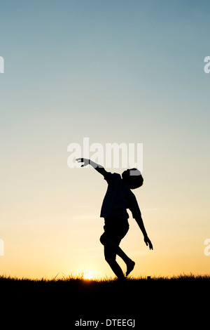Ragazzo round di filatura al tramonto. Silhouette Foto Stock
