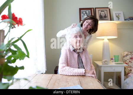 Figlia di pettinatura madre anziana i capelli in camera da letto Foto Stock