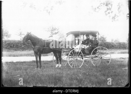 Questa fotografia mostra tre donne che cavalcano su una carrozza trainata da cavalli. L'immagine cattura un momento dell'inizio del XX secolo, evidenziando l'uso storico delle carrozze e il ruolo degli animali, come i cavalli, nel trasporto durante questo periodo. Foto Stock