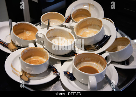 Un cameriere il vassoio pieno di svuotare le tazze di caffè. Foto Stock