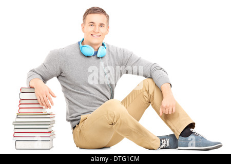 Giovane Uomo con cuffie appoggiato sulla pila di libri Foto Stock