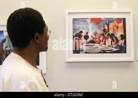 Porto di Spagna, Trinidad e Tobago. 17 feb 2014. Un visitatore orologi foto durante una mostra di 'bello Cina" nel porto di Spagna, Trinidad e Tobago, su Feb, 17, 2014. Il ministero della Cultura della Repubblica popolare cinese e di Confucio Institute of Trinidad e Tobago lunedì ha aperto la mostra fotografica di 'bello Cina", che mira a introdurre gli sviluppi in Cina negli ultimi anni e nel rafforzare le relazioni tra i due paesi. © Gao Xing/Xinhua/Alamy Live News Foto Stock