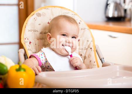 Sorridente baby a mangiare cibo da cucina Foto Stock