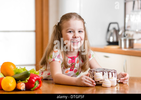 Kid scegliendo tra ortaggi sani e gustosi dolci Foto Stock