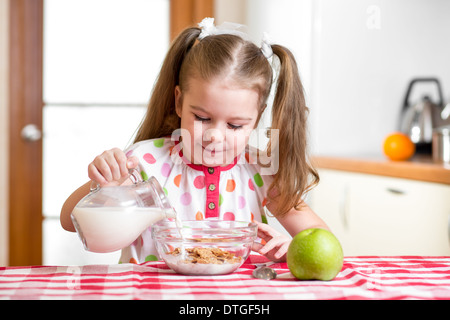 Kid girl preparare fiocchi di mais con il latte Foto Stock