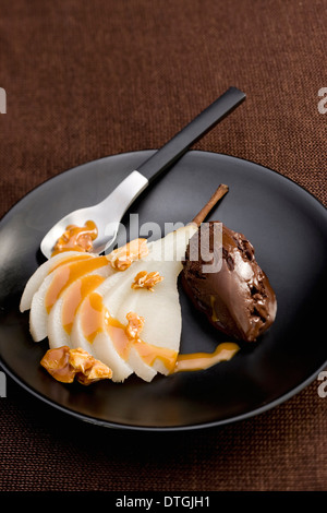 Pera affogata con salsa di caramello derivata,mandorle e gelato al cioccolato Foto Stock