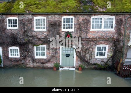 Una casa allagata con sacchi di sabbia proteggendo la porta anteriore dal fiume di acqua. Foto Stock