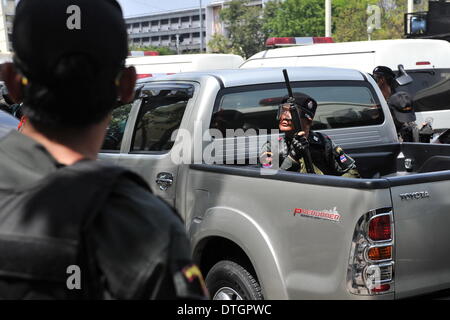 Bangkok, Tailandia. 18 Febbraio, 2014. Un Thai riot police officer detiene una pistola come egli cerca un cecchino in un edificio vicino durante gli scontri con anti-governo manifestanti vicino al monumento della democrazia in Bangkok, capitale della Thailandia, Feb 18, 2014. Polizia tailandese martedì mattina ha iniziato a recuperare dal governo anti-manifestanti cinque siti di rally nella capitale Bangkok, lasciando tre morti e 59 altri feriti negli scontri. Credito: Gao Jianjun/Xinhua/Alamy Live News Foto Stock