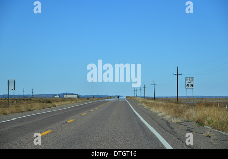 Route 66, Arizona, Stati Uniti. Lunga e dritta strada scompare nella distanza sotto un solitario blue sky, limite di velocità 65 Foto Stock