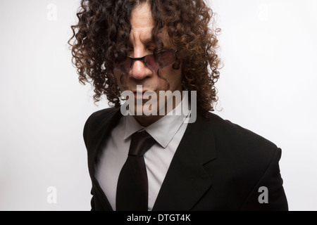 Ritagliato ritratto del mediterraneo cerca uomo con capelli ricci indossando business suit e occhiali da sole Foto Stock