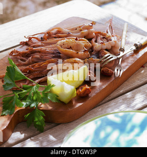 Polpo alla griglia su un tagliere Foto Stock