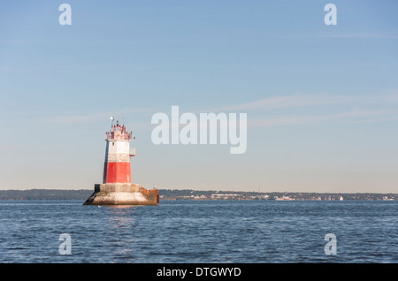 Grande colore bianco e rosso segno marini o beacon o un faro in mare. Bird sedersi sulla parte superiore del faro. Foto Stock