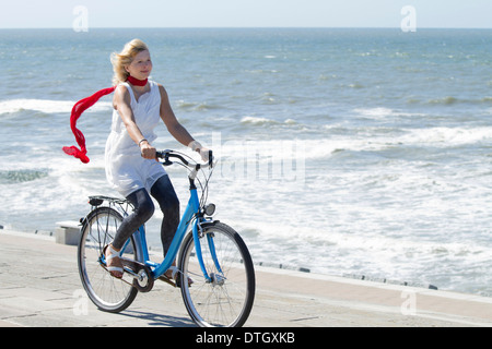 Donna bionda in abiti estivi in sella ad una bicicletta da mare, Bassa Sassonia, Germania Foto Stock