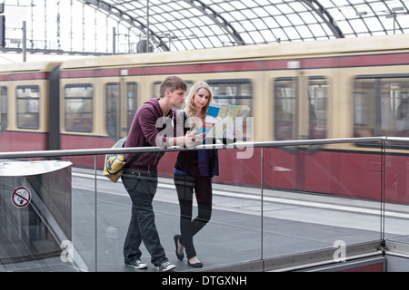 Coppia giovane in piedi sulla pedana e guardando una mappa di Berlino, Germania Foto Stock