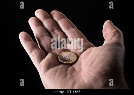 La mano di un uomo anziano con un euro moneta nel palmo della mano. Foto Stock