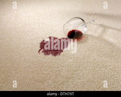 Eventuali fuoriuscite di vino rosso dal bicchiere di vino sul tappeto Foto Stock