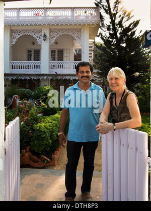 India Kerala, Fort Cochin, delizia Homestay, donna con il proprietario al cancello del dipinto di bianco guest house Foto Stock