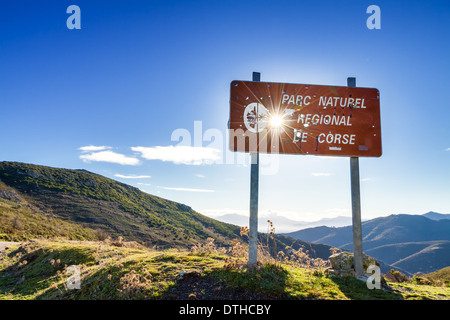 Parc Natural de Corse signpost riddled con il cacciatore fori di proiettile contro un Rising Sun Foto Stock