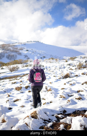 Giovane donna trekking in montagna innevata Foto Stock