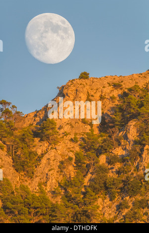 Real Full Moon Rising over Puig des Teix mountain al tramonto. Montagne Tramuntana, Deià, Maiorca, isole Baleari, Spagna Foto Stock