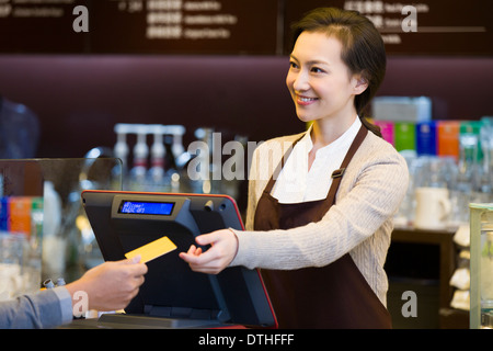 Il cliente di pagare con carta di credito in un coffee shop Foto Stock