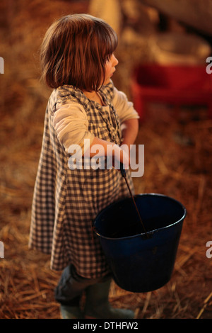 Bambini piccoli che desiderano dopo appena nato Agnelli Ovini in un granaio Foto Stock