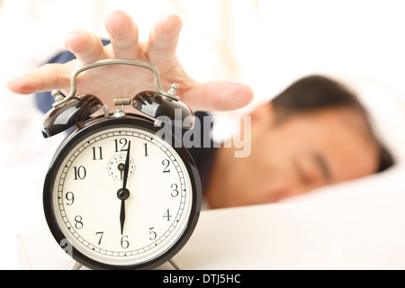 Uomo asiatico nel sonno, il risveglio di una sveglia Foto Stock