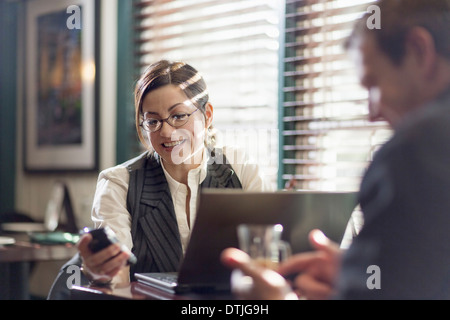 Una donna e uomo seduto alla scrivania di lavorare sia con l'utilizzo di telefoni smart nuova speranza in Pennsylvania USA Foto Stock