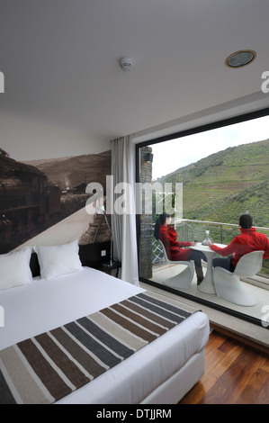 Coppia giovane seduto su un balcone a bere un bicchiere di vino Foto Stock