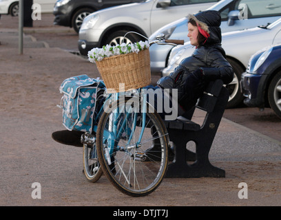Giovane donna si sedette sul banco di pubblico con la bicicletta, Exmouth, Devon, Regno Unito Foto Stock