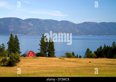 Granaio rosso e campi coltivati lungo il lago Flathead, Montana, USA. Foto Stock