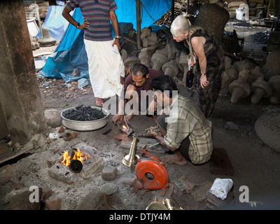 India Kerala, Mannar, metallo fonderia, donna occidentale visitatore guardando l'uomo rendendo la lampada in ottone Foto Stock