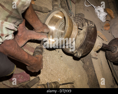 India Kerala, Mannar, metallo fonderia, uomo girando ottone fuso ciotola sul tornio Foto Stock