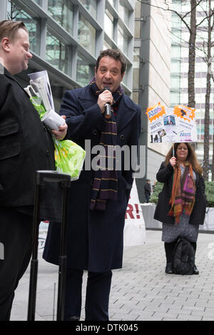 Sede ATOS, Londra, UK, 19 febbraio, 2014. Il comico e attivista Mark Tommaso parla al di fuori di ATOS con sede a Londra per protestare contro la società di attuazione di capacità di lavoro di valutazione. Gli attivisti chiedono la soppressione del lavoro di valutazione della capacità e ha dichiarato che un medico qualificato, idealmente il GP che regolarmente vede e tratta i malati o disabili singoli in questione, è l'unica persona in grado di decidere se un individuo è adatta per lavori. Credito: Patricia Phillips/Alamy Live News Foto Stock