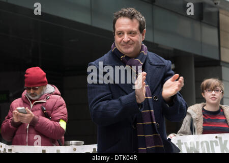 Sede ATOS, Londra, UK, 19 febbraio, 2014. Il comico e attivista Mark Thomas applaude dimostranti fuori ATOS Head Office di Londra. I manifestanti sostengono che i lavoratori ATOS con poca o nessuna conoscenza medica fare cattive decisioni che spingono le persone a perdere la loro indennità di malattia, e la domanda che un medico qualificato, idealmente il GP che regolarmente vede e tratta i malati o disabili la persona in questione è l'unica persona in grado di decidere se un individuo è adatta per lavori. Credito: Patricia Phillips/Alamy Live News Foto Stock