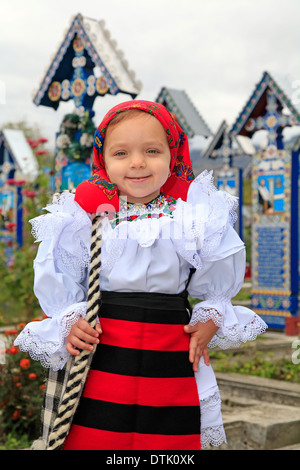Bambina indossa rumeno tradizionale abbigliamento tradizionale e cimitero di Sapanta su uno sfondo Foto Stock