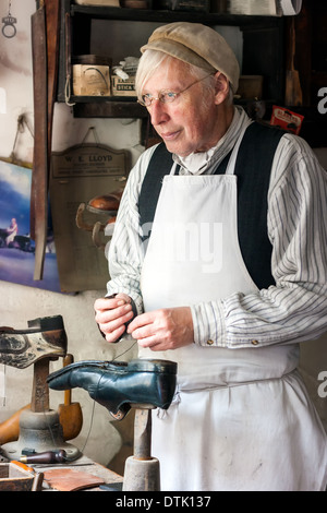 Uomo vestito in costume di lavoro come un calzolaio in cobblers workshop. Cittadina vittoriana Telford Inghilterra Foto Stock