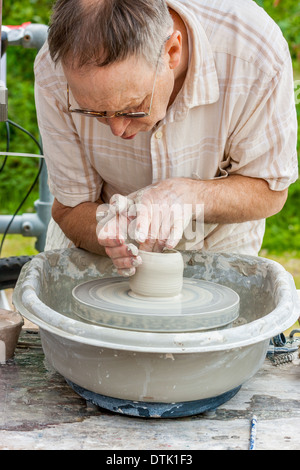 L'uomo la modellazione di argilla umida sulla pentola potters ruota all'aperto presso l'Etruria canal festival Etruria Stoke On Trent Staffordshire Inghilterra Foto Stock